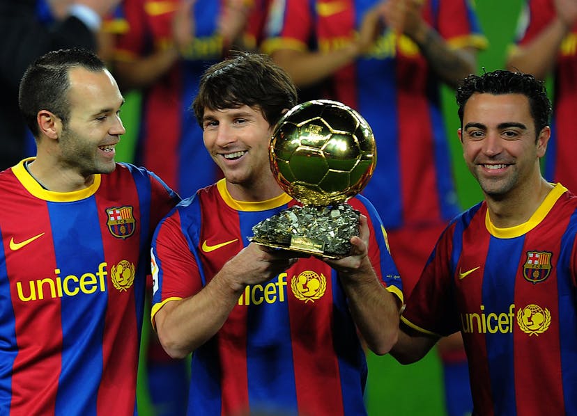 Barcelona's Argentinian forward Lionel Messi (C), flanked with Barcelona's midfielder Xavi Hernandez (R) and Barcelona's midfielder Andres Iniesta (L), poses with the 2010 Ballon d'Or trophy (Golden Ball) 