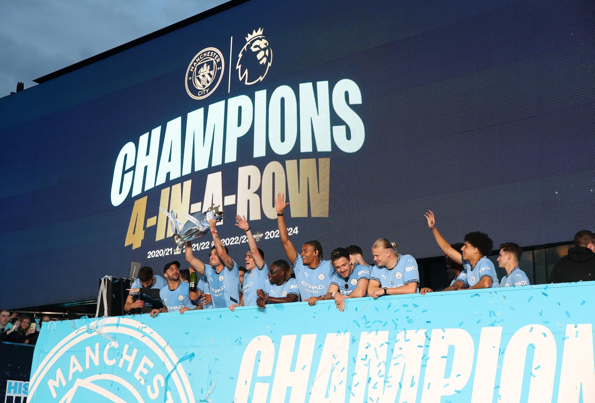 Players of Manchester City celebrate on the Open Top Bus with the Premier League trophy