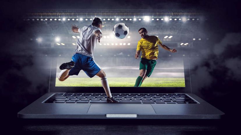 A laptop and two players with a soccer ball