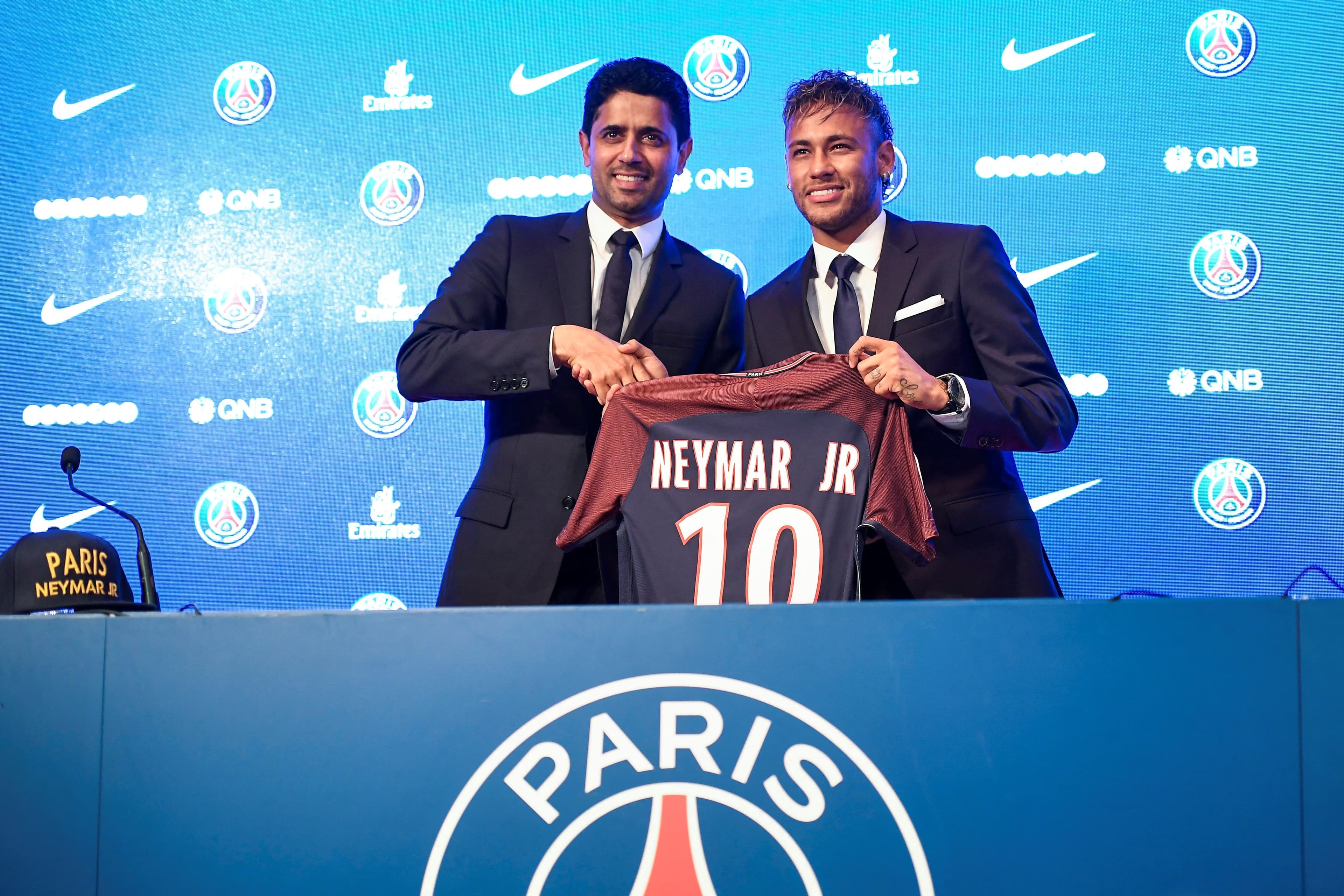 Brazilian superstar Neymar (R) poses with his jersey next to Paris Saint Germain's (PSG) Qatari president