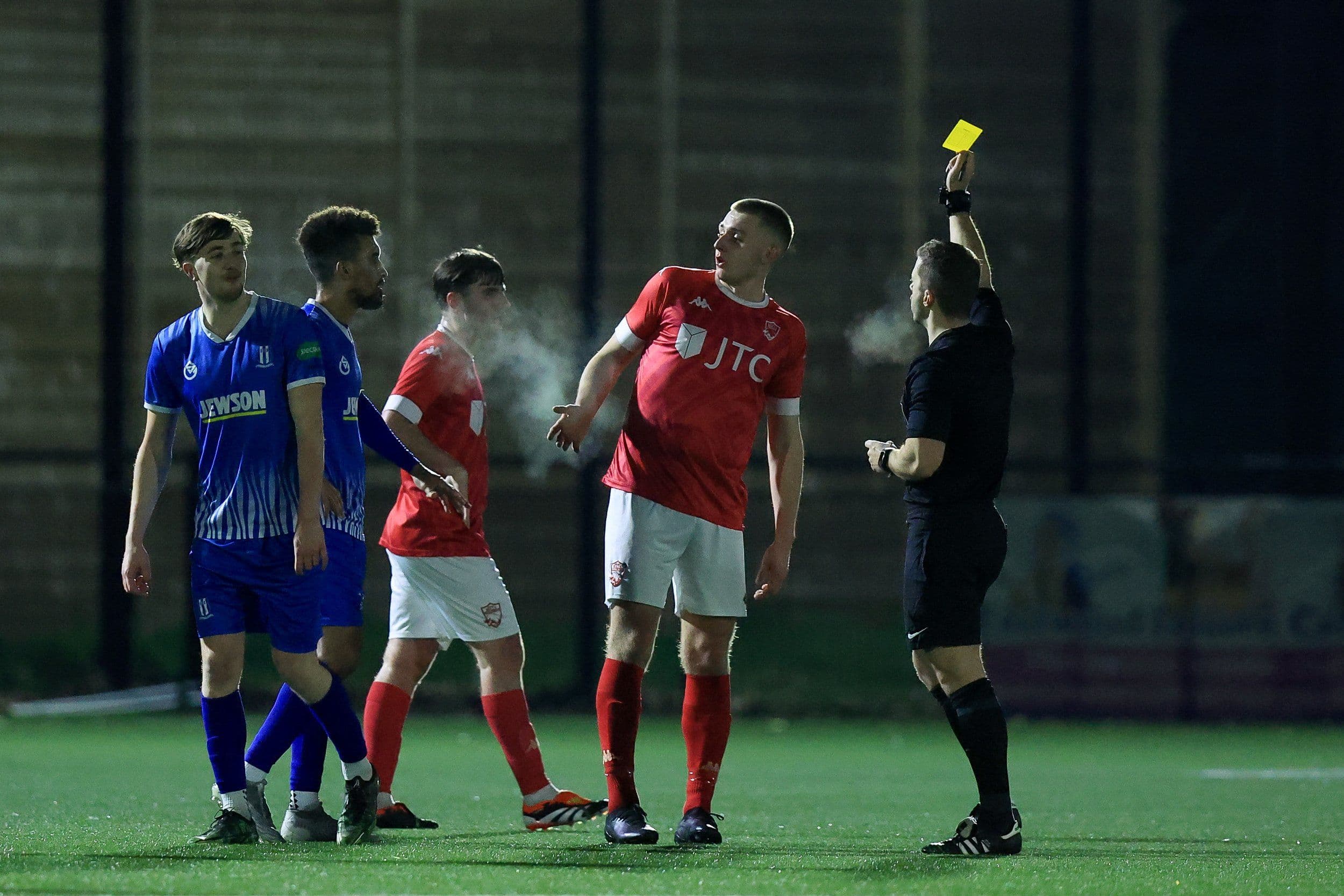 A referee showing a yellow card to a player during a football game. 