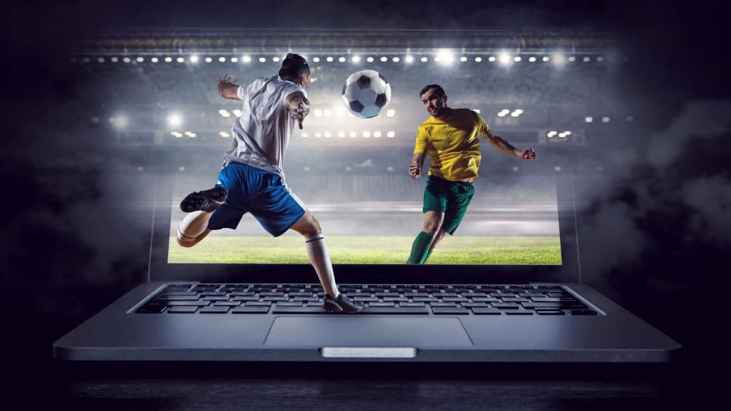 A laptop and two players with a soccer ball