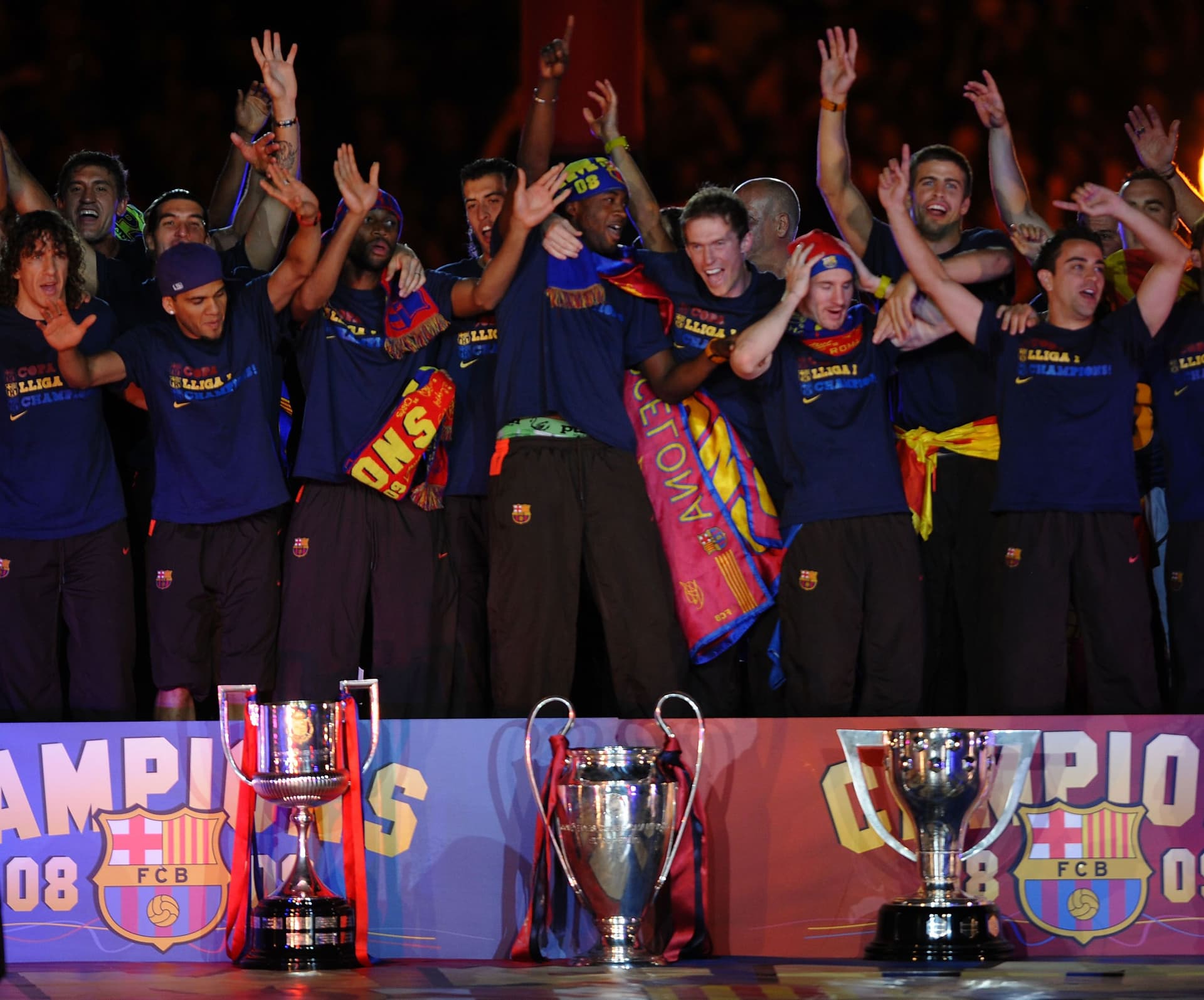 Barcelona players celebrate beside their three trophys