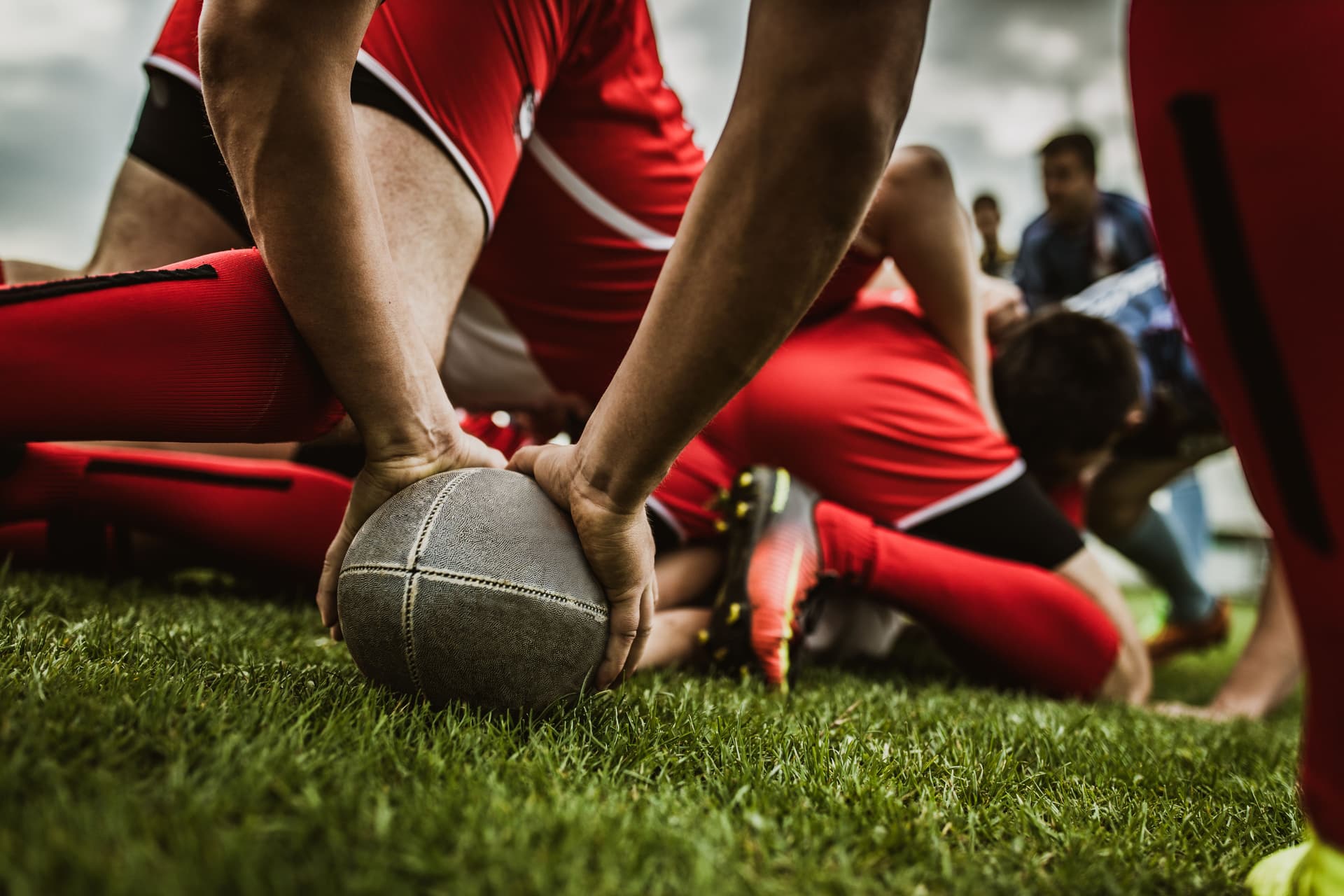 Close up of unrecognizable rugby player holding a ball on grass during a match at playing field