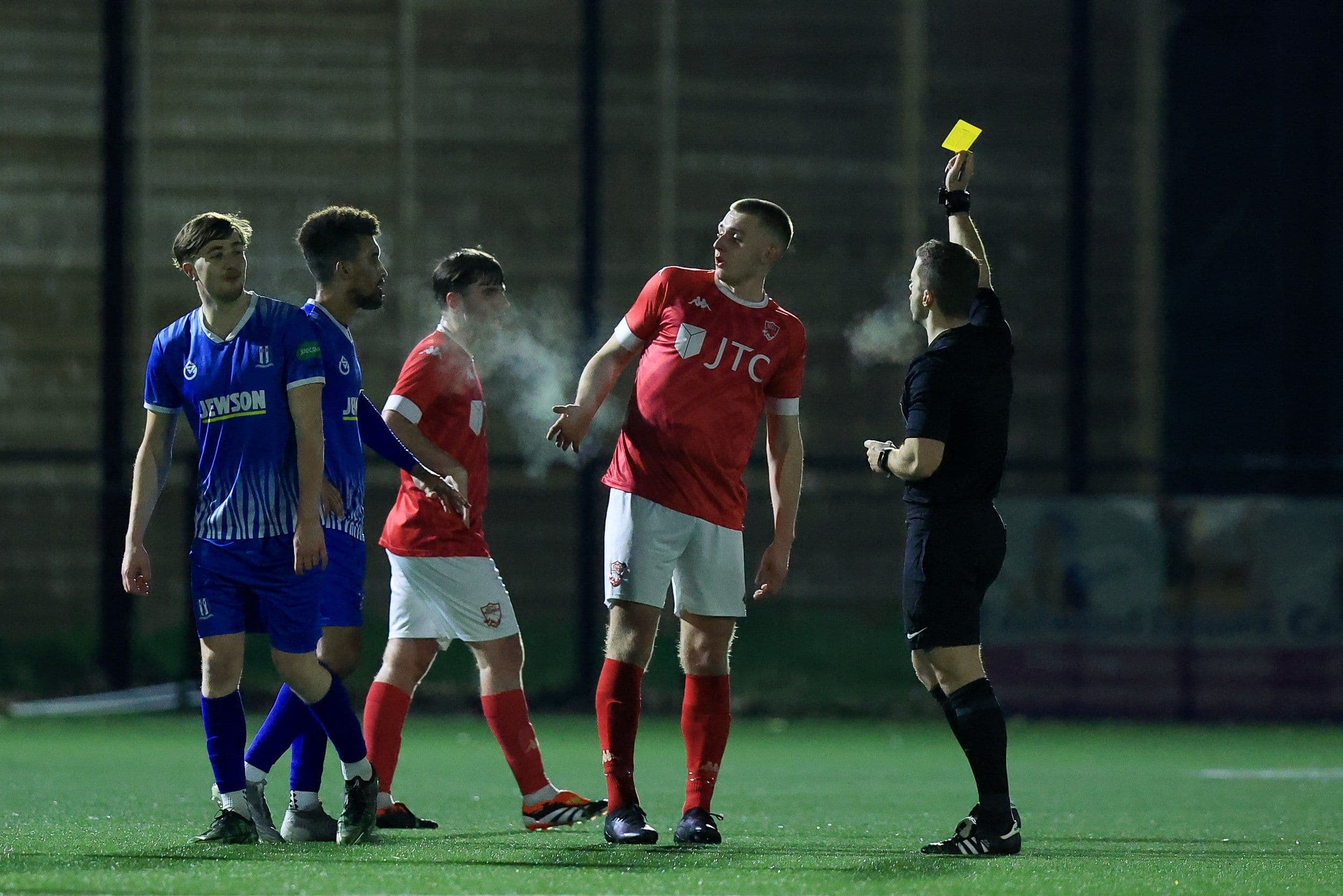 A referee showing a yellow card to a player during a football game.